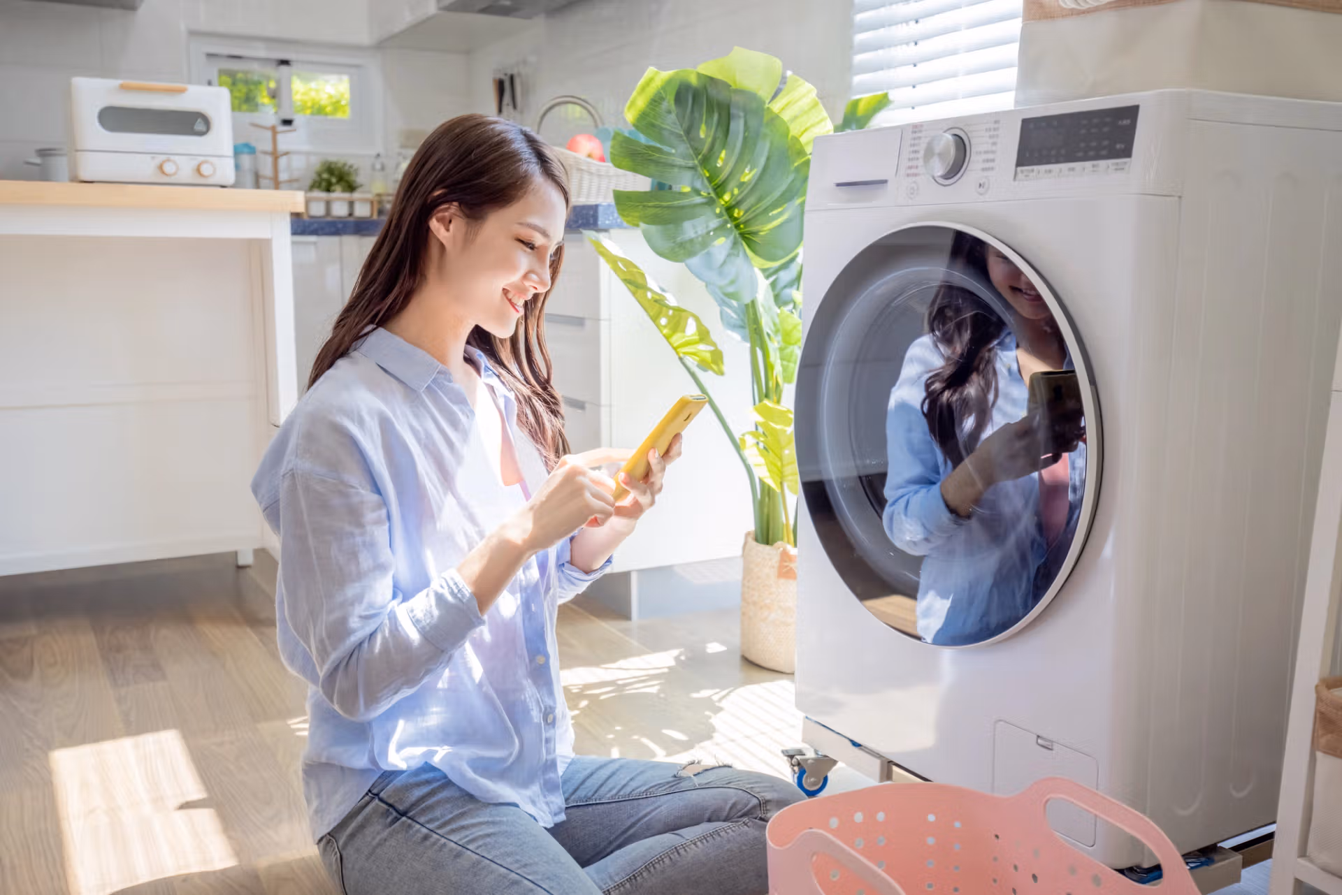 A woman is seated on the floor next to a washing machine, appearing calm and at ease in her home environment.