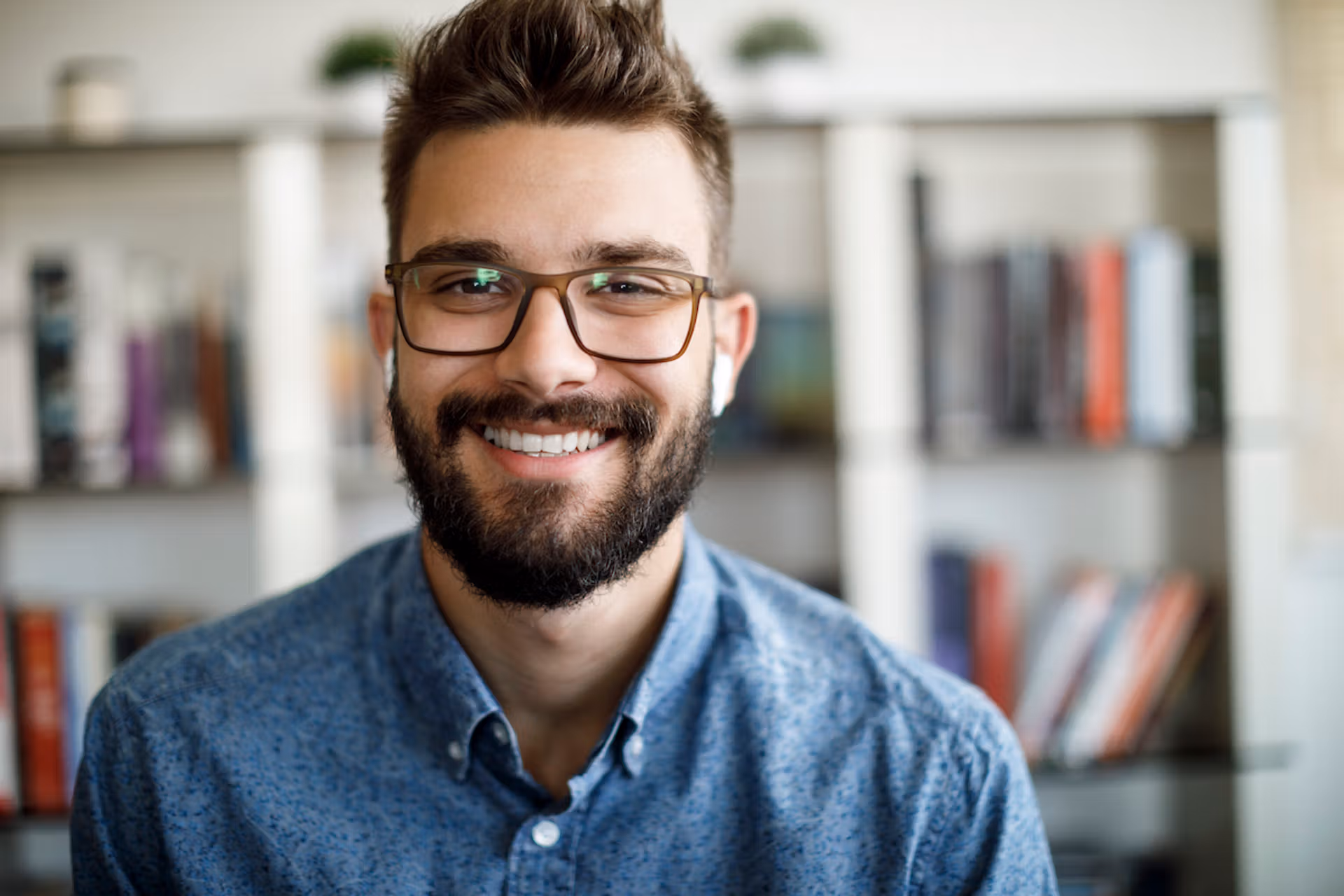 A cheerful man with glasses and a beard smiles at the camera, radiating friendliness and approachability.