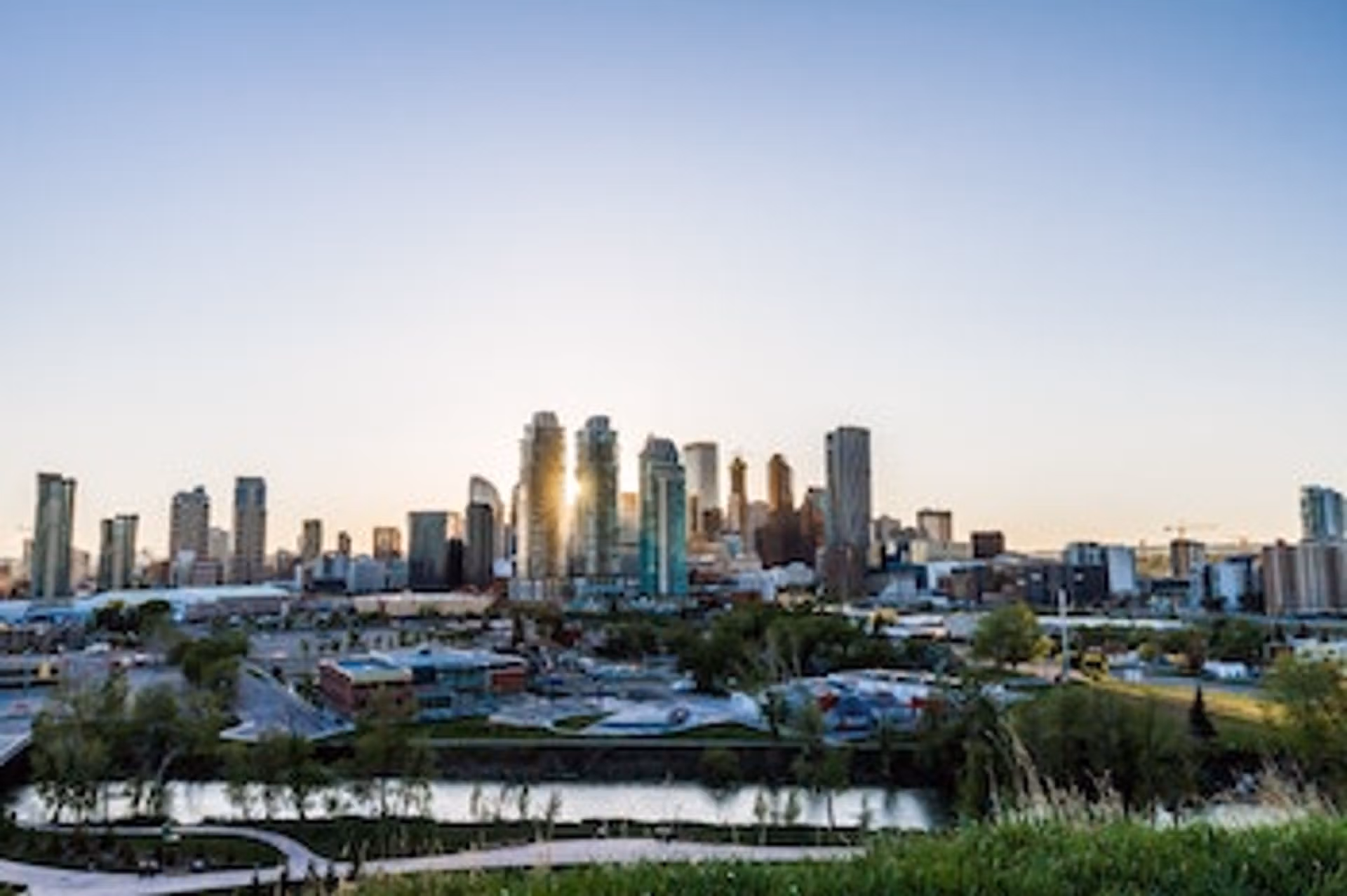 The skyline of a city at sunset, featuring a colorful sky with shades of orange and purple in the background.