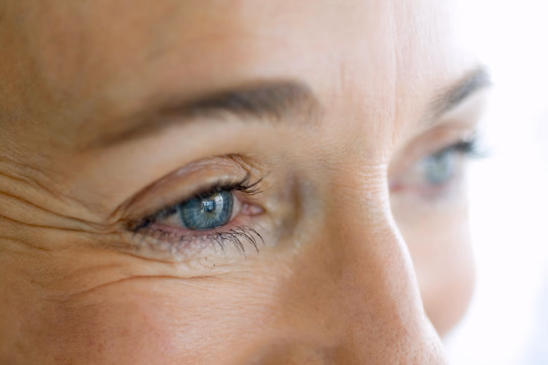 Close-up portrait of a woman, featuring prominent wrinkles that convey wisdom and maturity.