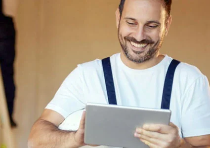 A man with a cheerful smile is holding a tablet computer, indicating enthusiasm and engagement with the device.