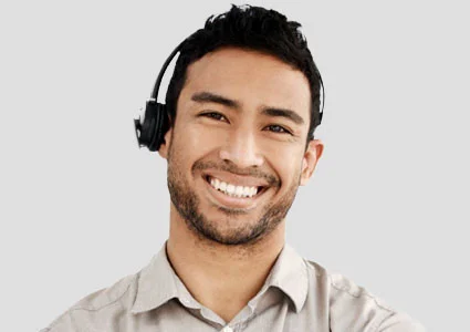 A smiling man wearing a headset, engaged in conversation or listening attentively.
