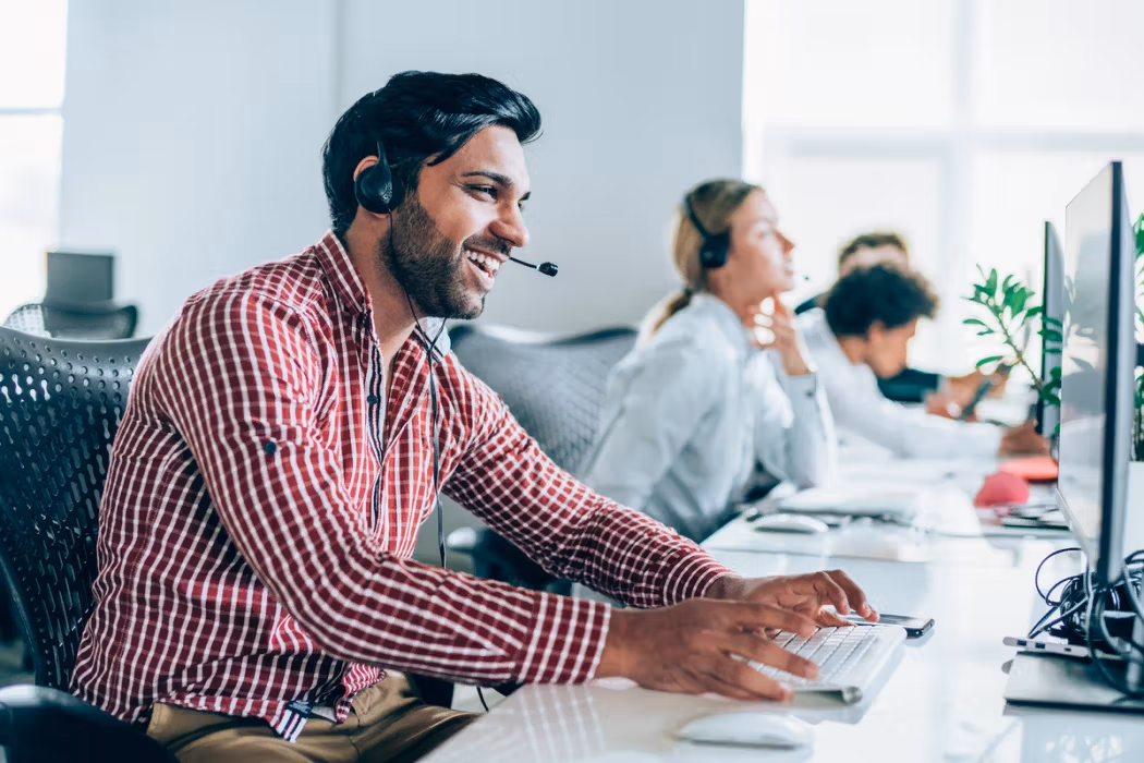 A professional man in an office setting, utilizing a headset for communication or work purposes.